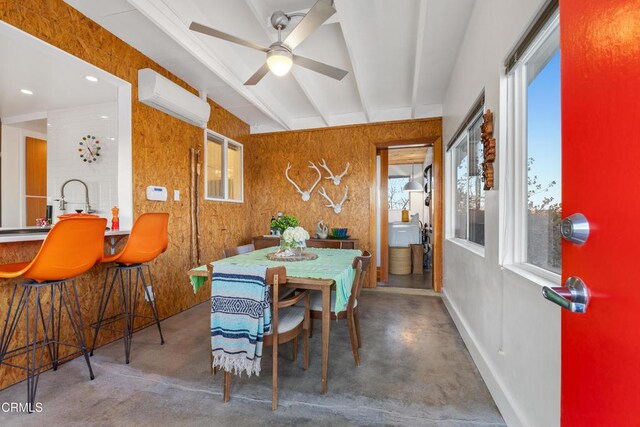 dining space with concrete flooring, ceiling fan, an AC wall unit, and wooden walls