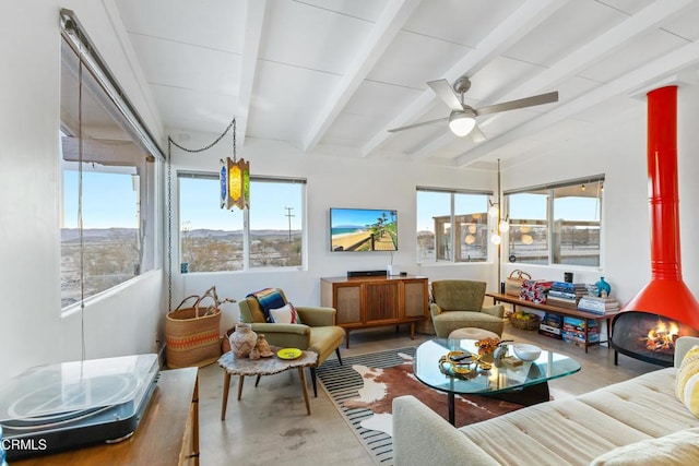 sunroom / solarium featuring ceiling fan, beam ceiling, and a wood stove