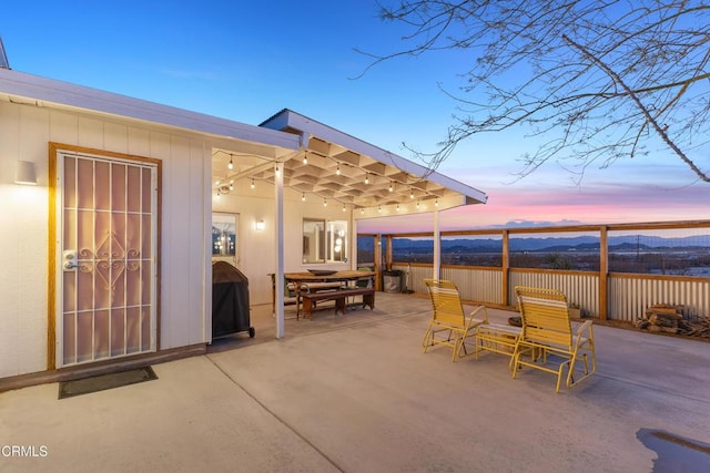 patio terrace at dusk featuring area for grilling and a mountain view