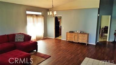 living room with dark hardwood / wood-style flooring, lofted ceiling, and an inviting chandelier