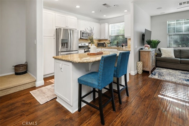 kitchen featuring white cabinets, a kitchen island, stainless steel appliances, and dark wood-type flooring