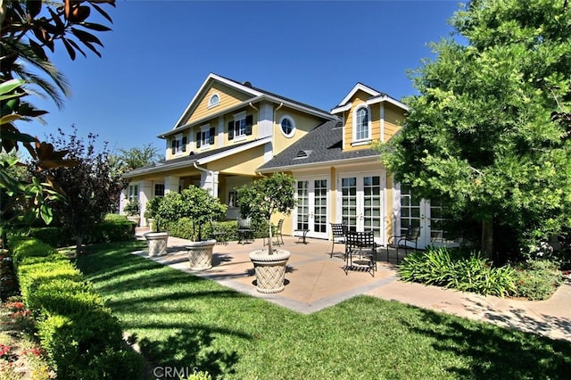 back of property with a yard, a patio, and french doors