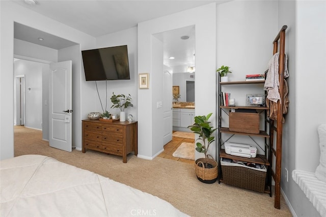 bedroom with ensuite bath and light colored carpet