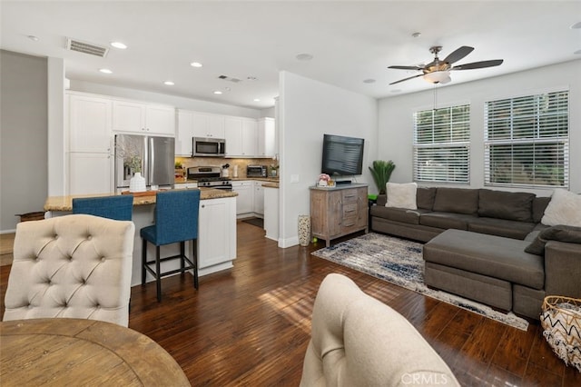 living room featuring ceiling fan and dark wood-type flooring