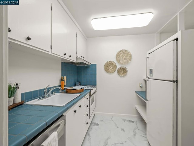 kitchen featuring white appliances, tile countertops, sink, and white cabinets