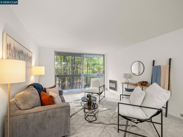 living room featuring heating unit, light colored carpet, and a wall of windows