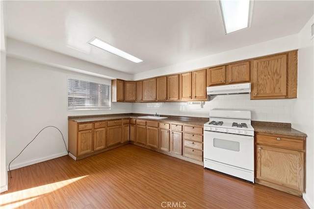 kitchen with white range with gas stovetop, hardwood / wood-style floors, tasteful backsplash, and sink