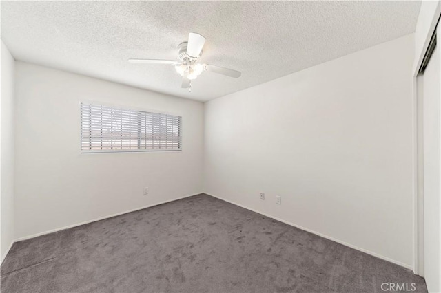 empty room with dark colored carpet, ceiling fan, and a textured ceiling