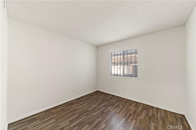 empty room with a textured ceiling and dark hardwood / wood-style flooring