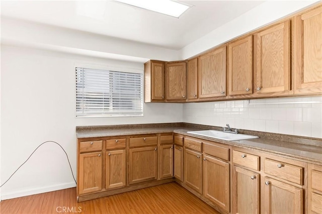 kitchen featuring backsplash, sink, and light hardwood / wood-style flooring