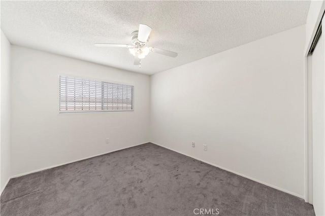 spare room with ceiling fan, dark carpet, and a textured ceiling