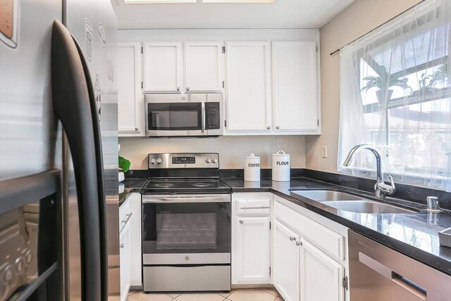 kitchen with light tile patterned floors, stainless steel appliances, sink, and white cabinets