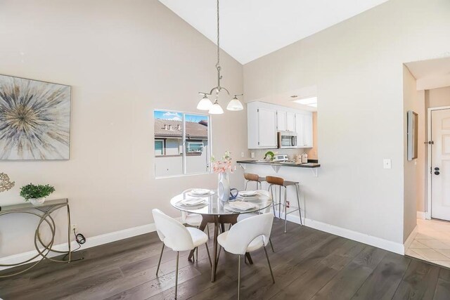 dining room featuring hardwood / wood-style flooring, high vaulted ceiling, and an inviting chandelier