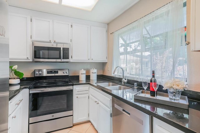 kitchen with white cabinetry, sink, stainless steel appliances, and light tile patterned flooring