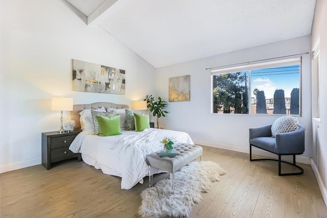 bedroom with high vaulted ceiling, hardwood / wood-style floors, and beam ceiling