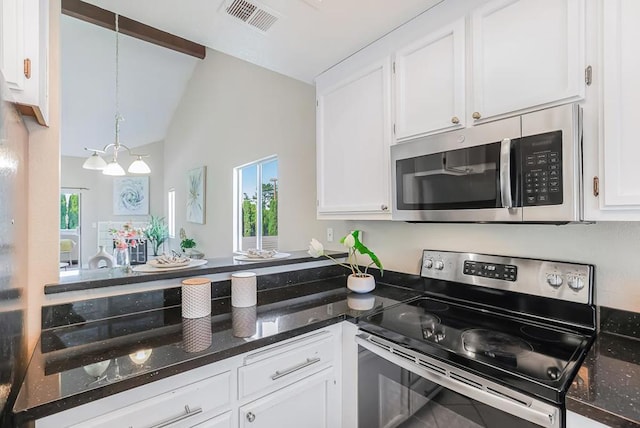 kitchen with white cabinetry, lofted ceiling, appliances with stainless steel finishes, and decorative light fixtures