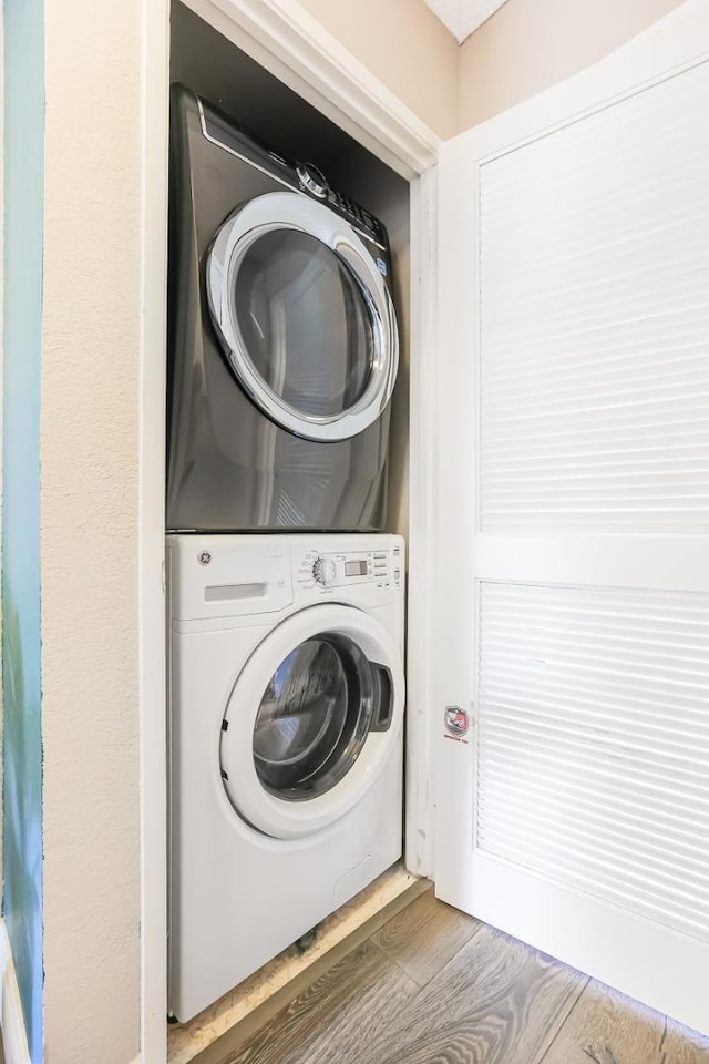 laundry area with wood-type flooring and stacked washer and clothes dryer