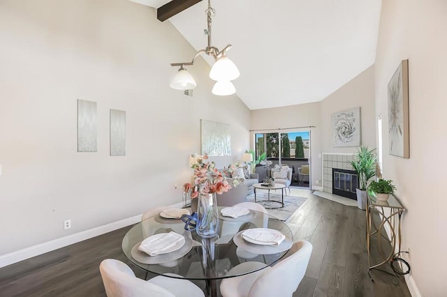 dining space with beam ceiling, high vaulted ceiling, dark hardwood / wood-style floors, a notable chandelier, and a fireplace