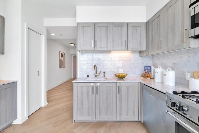 kitchen with gray cabinets, sink, appliances with stainless steel finishes, and light hardwood / wood-style flooring