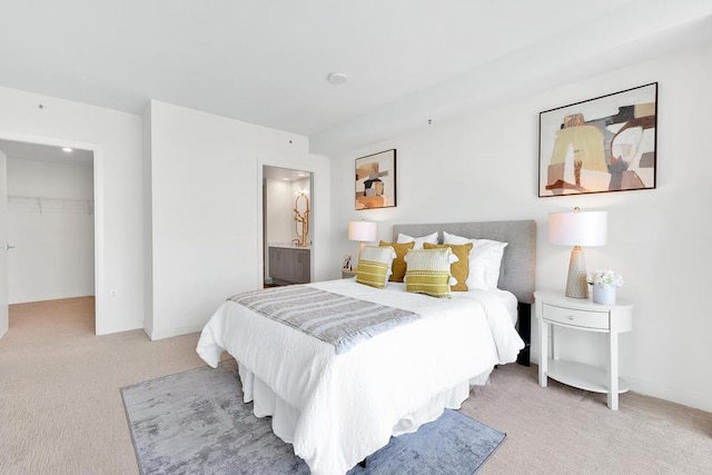 bedroom with ensuite bath, light carpet, a closet, and a spacious closet