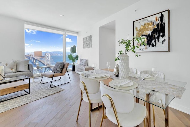 dining space featuring floor to ceiling windows, a water view, and light hardwood / wood-style floors