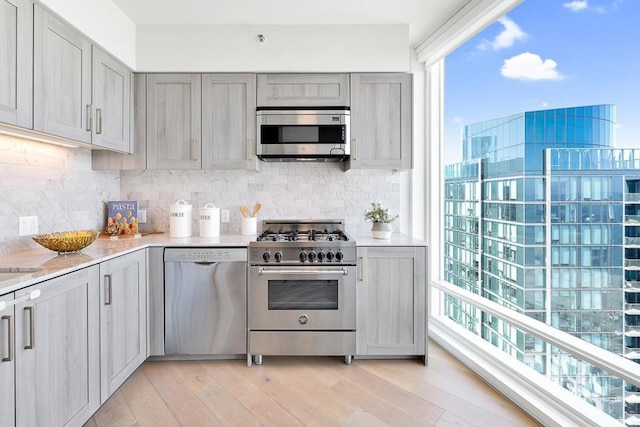 kitchen with gray cabinets, stainless steel appliances, and tasteful backsplash