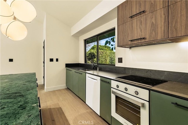 kitchen featuring sink, light hardwood / wood-style flooring, black electric stovetop, vaulted ceiling, and oven