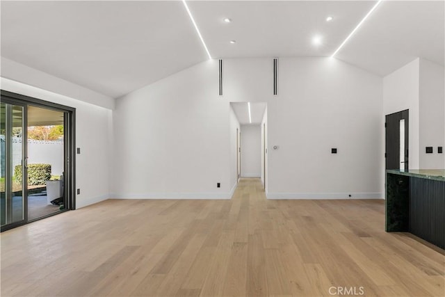 unfurnished living room featuring lofted ceiling and light hardwood / wood-style flooring