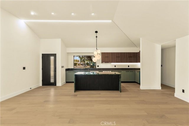 kitchen with hanging light fixtures, a kitchen island, dark brown cabinets, and light hardwood / wood-style floors