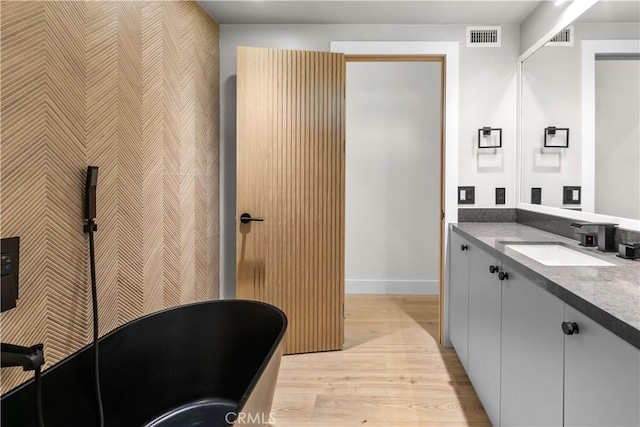 bathroom with vanity, hardwood / wood-style floors, and a bathtub