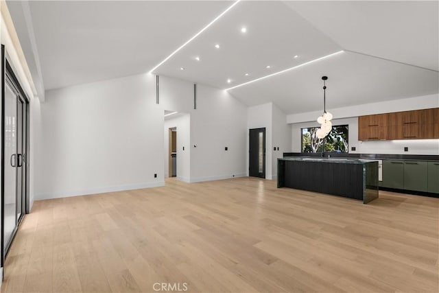 kitchen featuring hanging light fixtures, an island with sink, lofted ceiling, and light hardwood / wood-style flooring