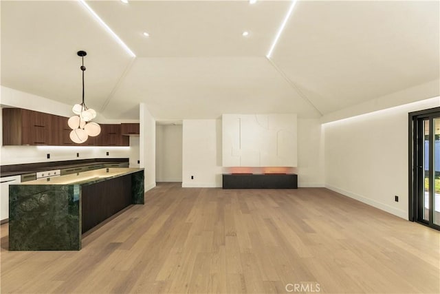 kitchen featuring lofted ceiling, dark brown cabinets, light hardwood / wood-style flooring, and decorative light fixtures