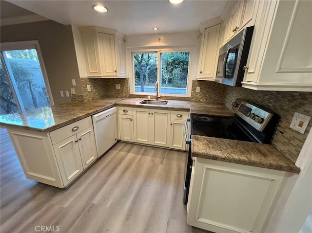 kitchen with white cabinetry, kitchen peninsula, stainless steel appliances, tasteful backsplash, and sink