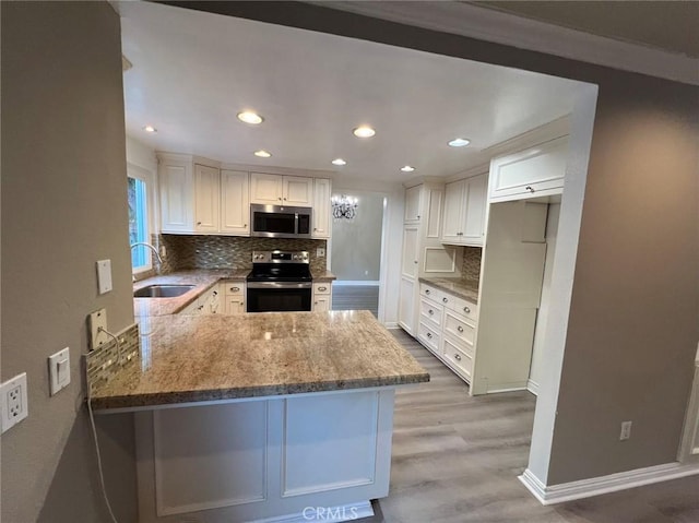 kitchen with kitchen peninsula, stainless steel appliances, white cabinets, light hardwood / wood-style flooring, and sink