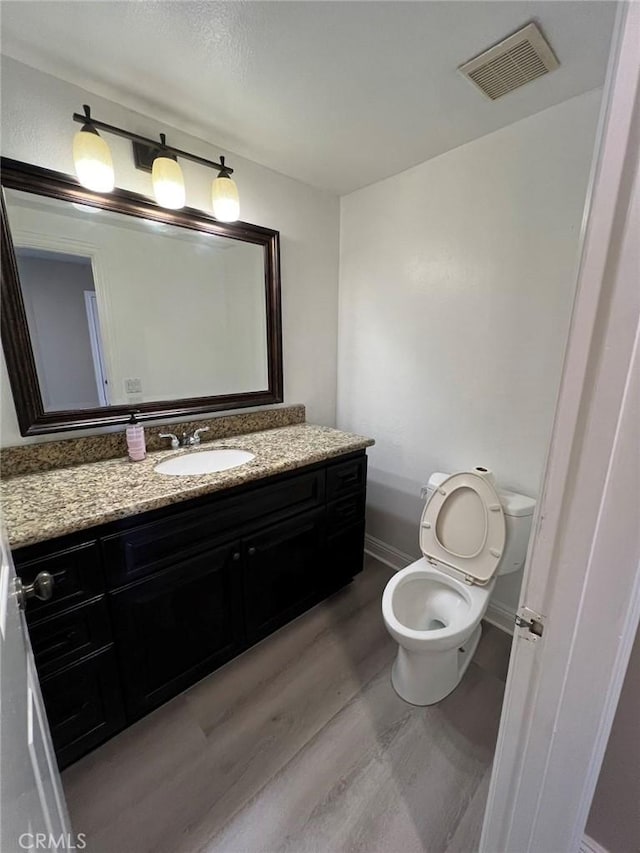 bathroom with toilet, hardwood / wood-style floors, and vanity