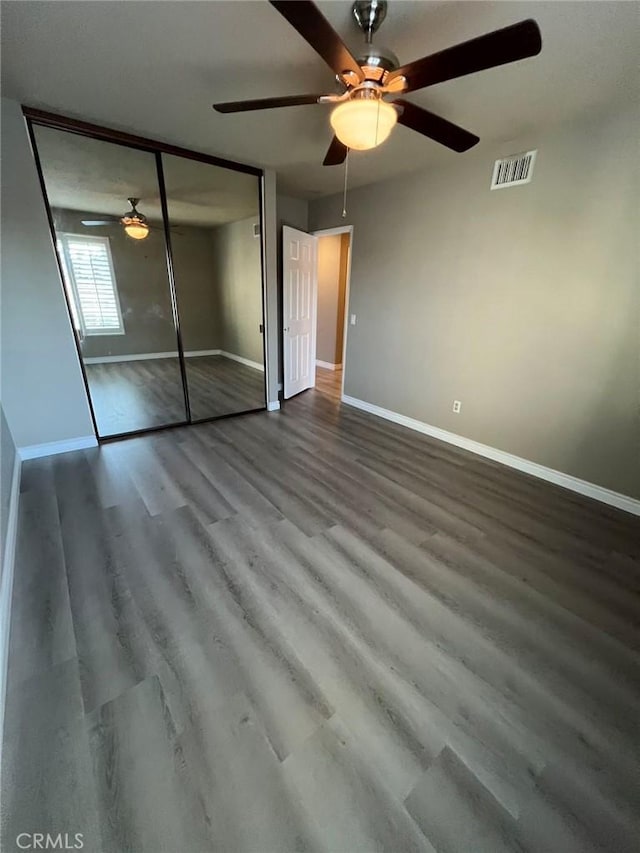 unfurnished bedroom featuring ceiling fan, hardwood / wood-style flooring, and a closet