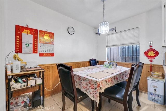 tiled dining space featuring wood walls