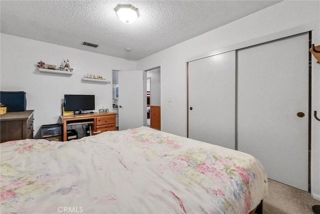 carpeted bedroom with a closet and a textured ceiling