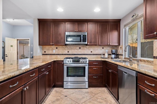 kitchen featuring light stone counters, sink, light tile patterned flooring, and stainless steel appliances