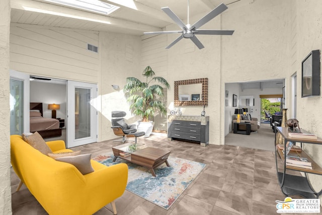 interior space featuring high vaulted ceiling, french doors, a skylight, ceiling fan, and beam ceiling