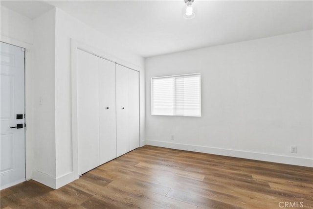 unfurnished bedroom featuring hardwood / wood-style floors and a closet