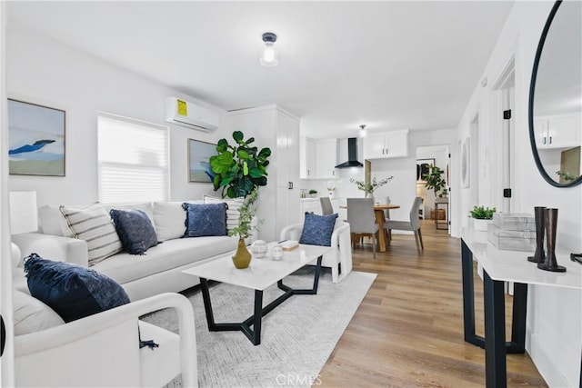 living room with a wall mounted air conditioner and light hardwood / wood-style flooring