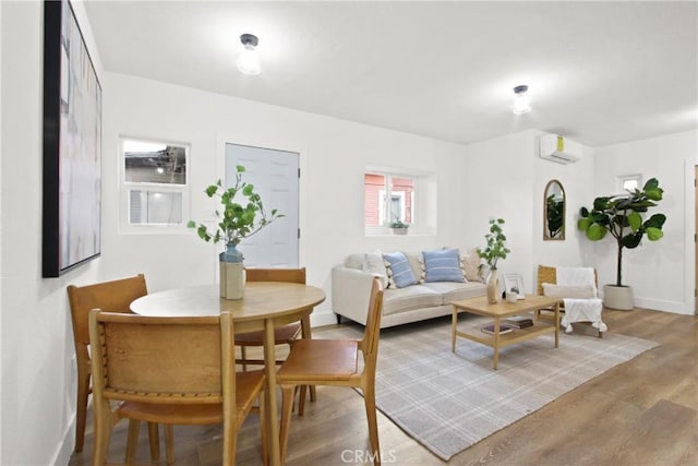 living room with a wall mounted air conditioner and hardwood / wood-style flooring