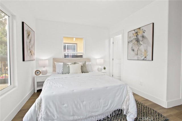 bedroom with dark hardwood / wood-style flooring and multiple windows