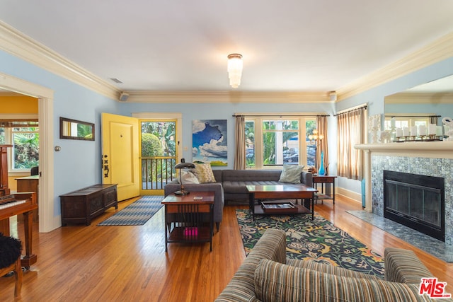 living room featuring light wood-type flooring, crown molding, and a high end fireplace