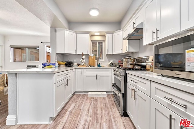 kitchen featuring white cabinets, kitchen peninsula, appliances with stainless steel finishes, and light hardwood / wood-style flooring