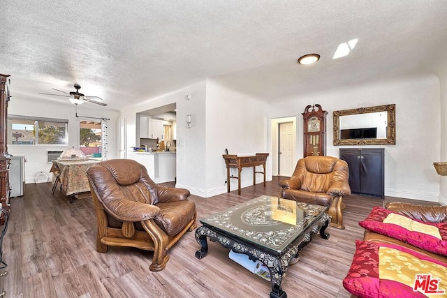 living room with ceiling fan, light hardwood / wood-style floors, and a textured ceiling