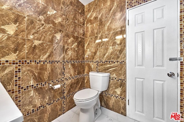 bathroom featuring toilet and tile walls