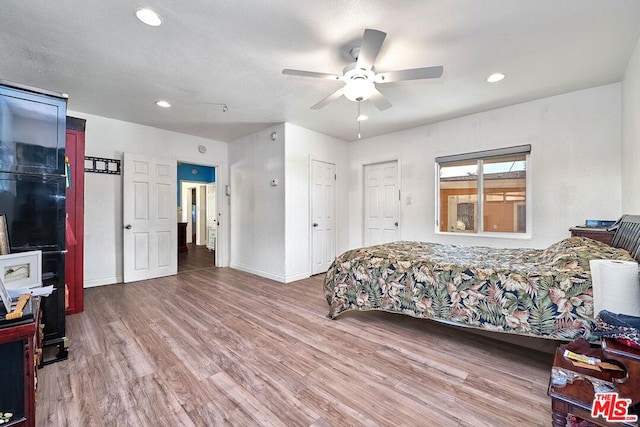 bedroom with ceiling fan, light hardwood / wood-style floors, and a textured ceiling