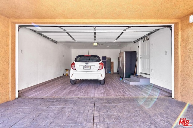 garage with a garage door opener and stainless steel refrigerator